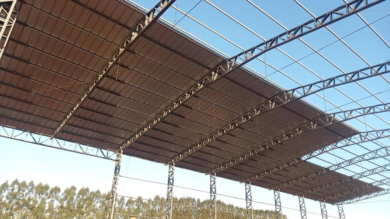 Estrutura metálica de cobertura industrial de grande vão totalmente montada sobre pilares de concreto, com tesouras metálicas treliçadas
