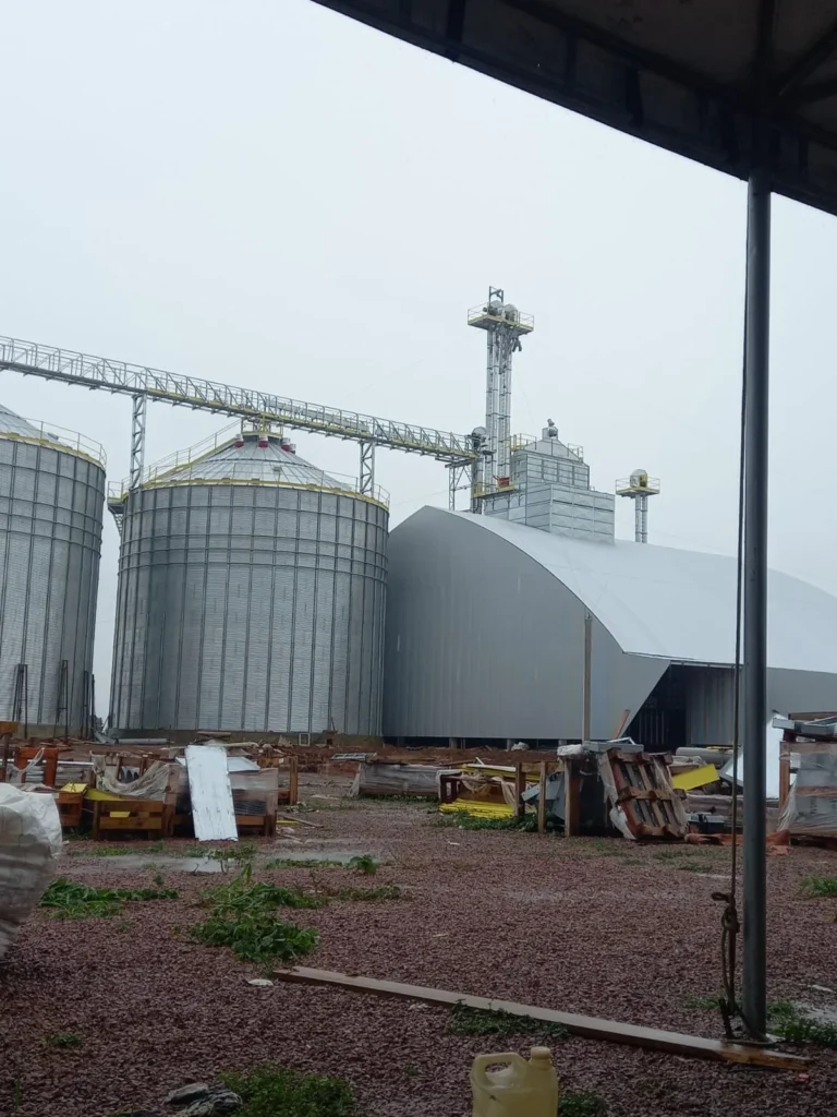 Vista ampla de unidade armazenadora com silos, armazém e estruturas elevadas